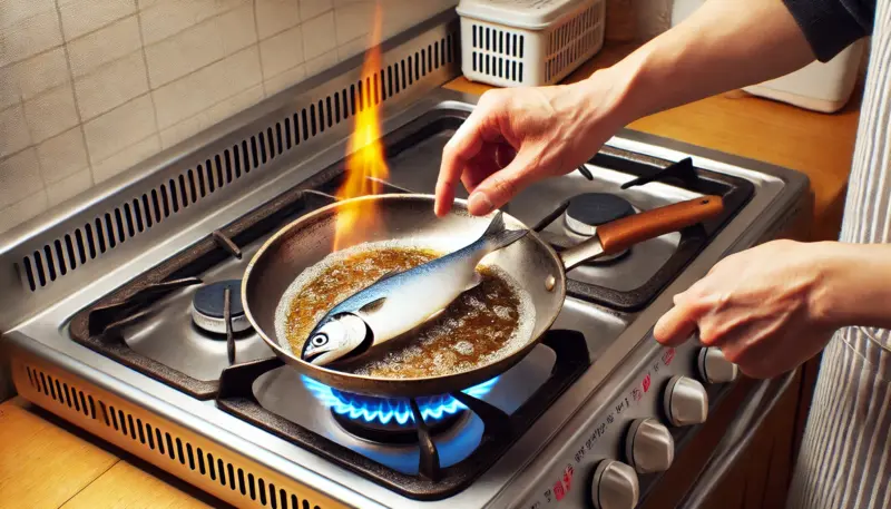 日本のキッチンで、ガス火の中央だけが強く当たったステンレスフライパンに魚をのせ、予熱不足で焦げ付き始めている調理ミスの例