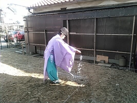 地鎮祭。神主が土地にお米とお酒を撒いて土地を清めていく写真