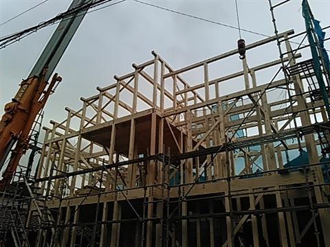 新築地鎮祭風景。木造住宅の骨組みをクレーン車を使い、大工が組み上げていく写真