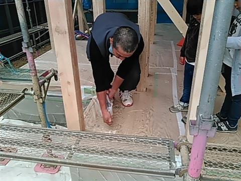 上棟式。木造住宅骨組みが出来き、建物内でお酒を撒いて清めている写真