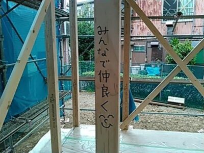 上棟式。木造住宅の骨組みに子供が絵を描いている