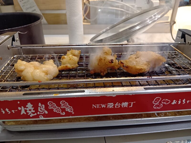 換気扇の下で「屋台横丁」コンロで焼肉をしている写真。ホルモンから煙が出ている様子