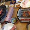ダイニングテーブルで焼肉をする様子。コンロから肉の煙が出ている写真