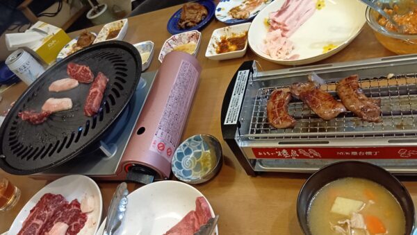 ダイニングテーブルで焼肉をする様子。コンロから肉の煙が出ている写真