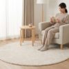 パーソナルチェアとサイドテーブル、円形のオフホワイトIKEA ストエンセ ラグが配置された、柔らかな雰囲気の読書コーナー。日本人女性がリラックスしている。